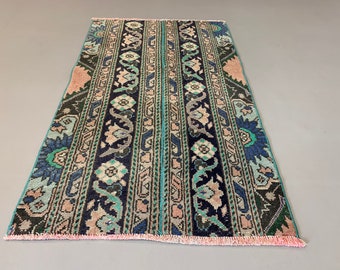 May include: A vintage rug with a blue, green, and pink floral pattern. The rug has a fringe border and is made of wool.
