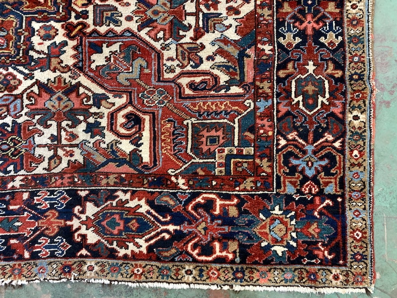 May include: Close-up of a traditional Persian rug with intricate patterns in shades of red, blue, and cream. The rug has a fringe border and is woven with a high knot count.