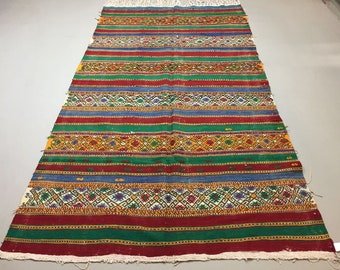 May include: A colorful striped rug with intricate geometric patterns in shades of red, green, blue, yellow, and white.