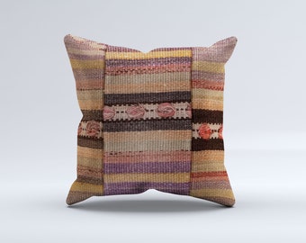 May include: Square decorative pillow with a woven, striped design in shades of purple, pink, brown, and beige. The pillow features a textured surface and a unique pattern, adding a touch of rustic charm to any space.