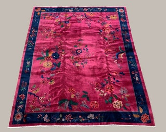 May include: A vintage Chinese rug with a pink background and a blue border. The rug features a floral pattern with intricate details.