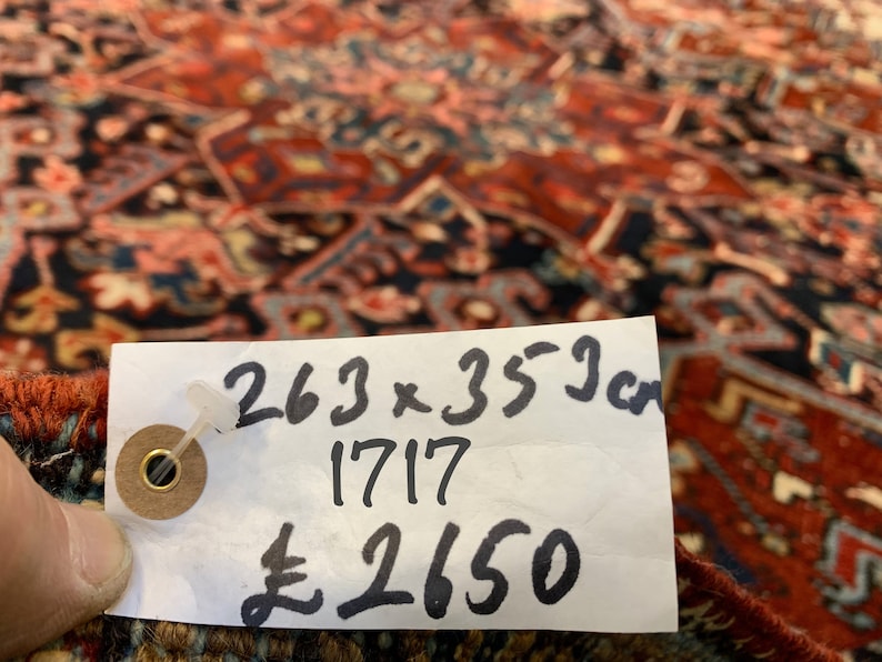 May include: A white tag with black writing on a red and blue patterned rug. The tag reads "263 x 353 cm 1717 &pound;2650".