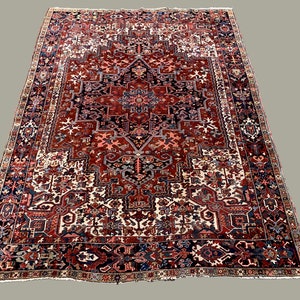 May include: A large, intricately patterned rug with a red, blue, and white color scheme. The rug features a central medallion with a geometric design and a border with floral motifs.