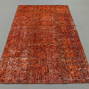May include: A vintage-style rug with a faded, distressed look. The rug is a patchwork of different patterns and colors, with a predominantly orange and brown color scheme.