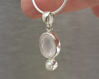 Puede incluir: Un collar de plata con un colgante de cuarzo rosa y un pequeño dije de perla.