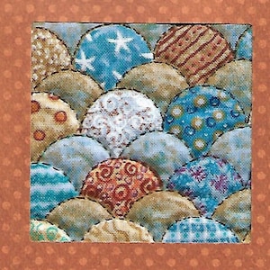 May include: A square textile piece featuring a repeating pattern of overlapping, semi-circular shapes. The shapes are filled with various patterns, including stars, stripes, and floral designs, in shades of blue, tan, and red. The border is a solid orange with small white dots.