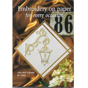 Puede incluir: Portada de libro con el título "Bordado en papel para cada ocasión". Presenta un diseño bordado en oro de una linterna y volutas sobre un fondo en forma de diamante blanco y dorado. El número 86 es visible.