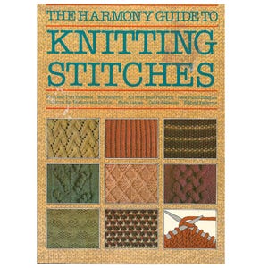 Könnte beinhalten: Ein Buch mit dem Titel "THE HARMONY GUIDE TO KNITTING STITCHES" mit einem beigefarbenen Einband und türkisfarbener Schrift. Das Cover zeigt verschiedene Strickmuster in verschiedenen Farben, darunter Grün, Orange und Braun. Das Buch listet auch verschiedene Strickmuster auf.