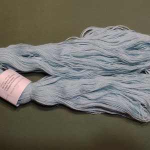 May include: A skein of light blue embroidery floss, with a white label that reads "DMC 435 - 100% Mercerized Cotton - Colour Fast - Washable - Made in France - DMC 100% Coton Mercerisé - Coloris Inaltérable - Lavable - Fabriqué en France - DMC", and a DMC logo.