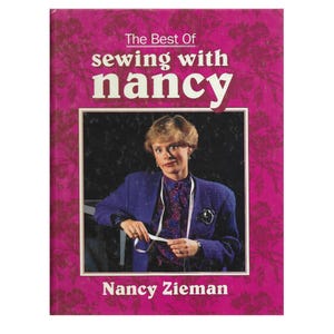 May include: A book cover featuring a pink floral design and the title "The Best Of sewing with nancy" in white and red. The central image is a photo of Nancy Zieman wearing a blue blazer. The author's name, Nancy Zieman, is at the bottom.
