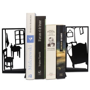 May include: Black metal bookends with cut-out room scenes frame a collection of books. The books have various colored spines and titles, including "Malczewski" and "Souvenirs et Romans". The bookends add a decorative touch to any bookshelf.