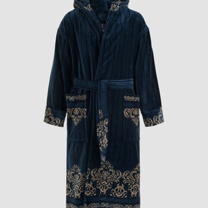 Op de afbeelding: Een donkerblauwe badjas met capuchon en een gouden patroon. De badjas heeft een strikceintuur en zakken.