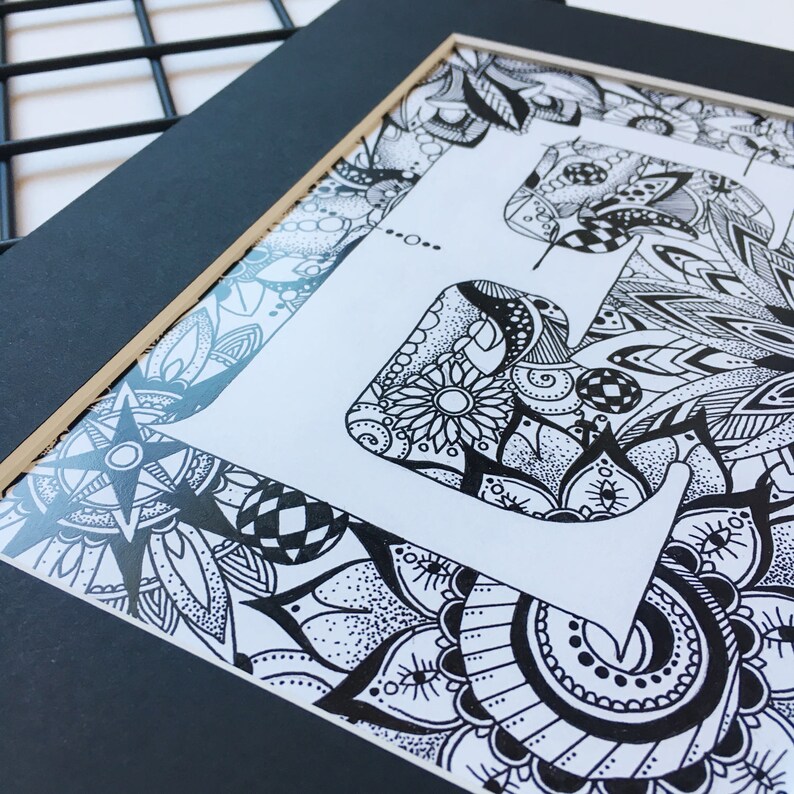 May include: Black and white framed art print featuring a stylized letter 'F' with intricate floral and geometric patterns.