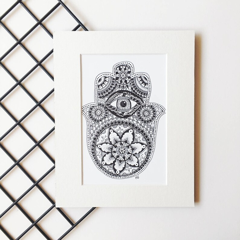 May include: A black and white hand-drawn illustration of a hamsa, also known as the Hand of Fatima, with a detailed mandala design and an eye in the center.