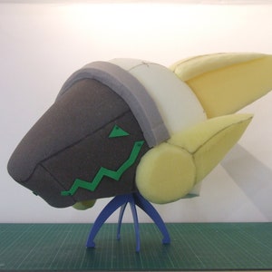 May include: A foam head sculpture with a yellow and white head and a brown face. The head is on a blue stand.