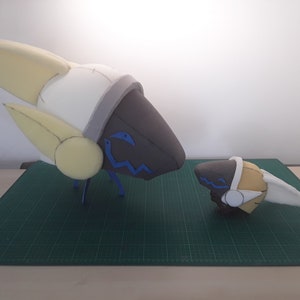 May include: Two foam model heads, one large and one small, with white, yellow, and gray accents. The larger head has blue details on the face. Both heads have a wavy blue line on the face.