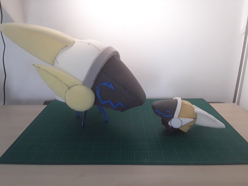 May include: Two foam model heads, one large and one small, with white, yellow, and gray accents. The larger head has blue details on the face. Both heads have a wavy blue line on the face.