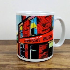 May include: White ceramic mug with a colorful illustration of a brick building with a sign that reads "Henderson's Relish, Sheffield, Ltd."