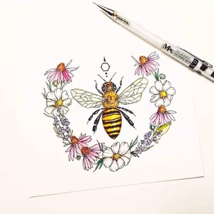 Puede incluir: Una ilustraci&oacute;n dibujada a mano de una abeja rodeada de una corona de flores rosas y blancas. La abeja es amarilla y negra con alas detalladas. Las flores est&aacute;n dibujadas en un estilo delicado con p&eacute;talos rosas y blancos.