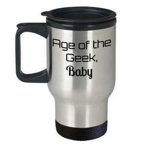 May include: A silver travel mug with a black lid and handle. The mug has the text "Age of the Geek, Baby" printed on it.