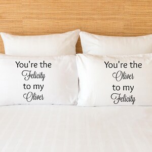 May include: Two white pillowcases with black text. The text on the left pillowcase reads "You're the Felicity to my Oliver". The text on the right pillowcase reads "You're the Oliver to my Felicity".