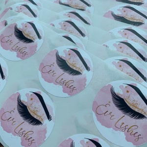May include: A sheet of pink and white round stickers with a black and gold eyelash design and the text "Cir Lashes".