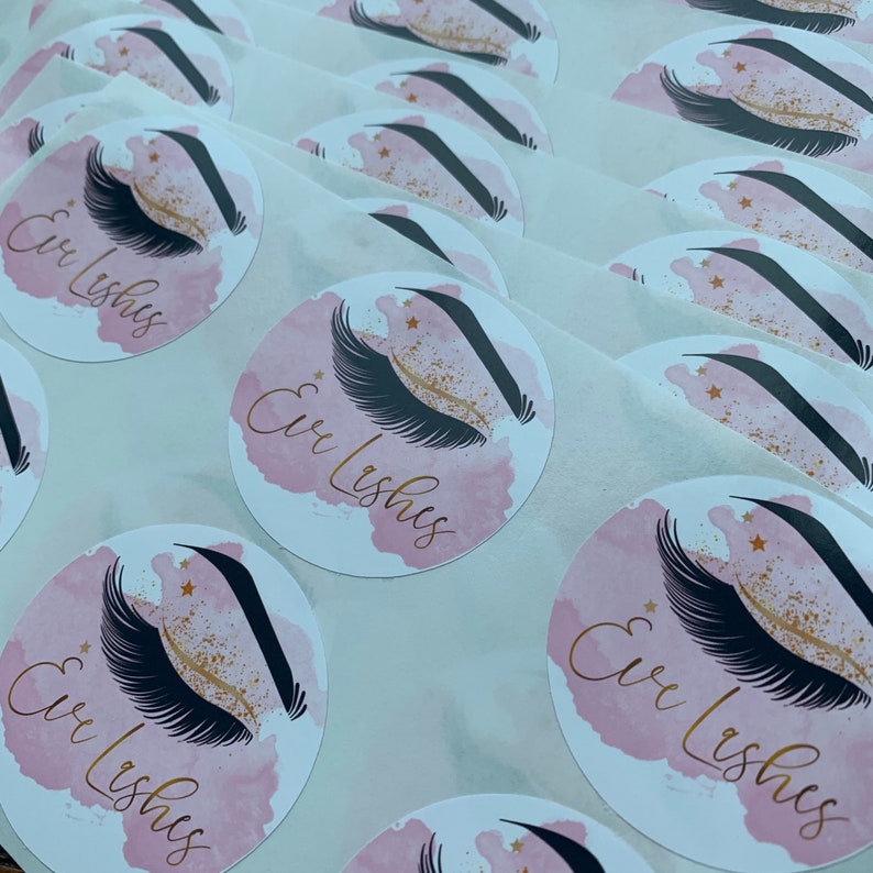 May include: A sheet of pink and white round stickers with a black and gold eyelash design and the text "Cir Lashes".