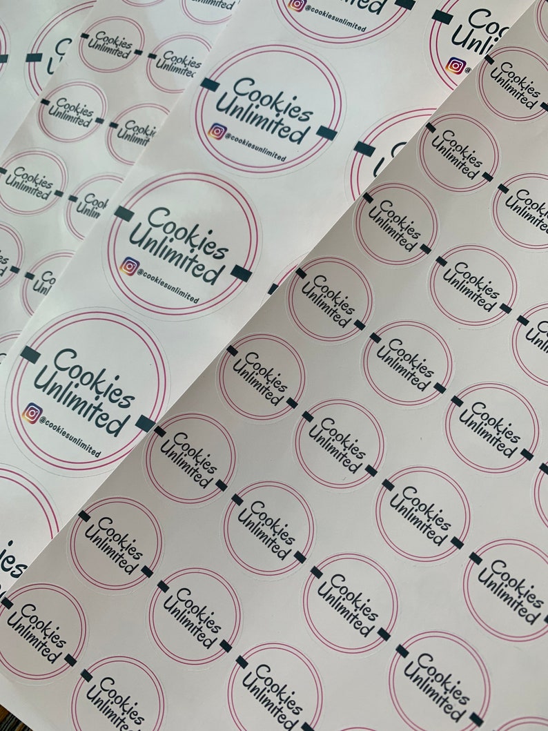 May include: A sheet of white stickers with the text "Cookies Unlimited" and the social media handle "@cookiesunlimited" printed in black and pink. The stickers are arranged in rows and columns.