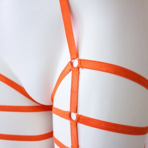 Op de afbeelding: Oranje verstelbare kousenband met meerdere banden en metalen ringen.