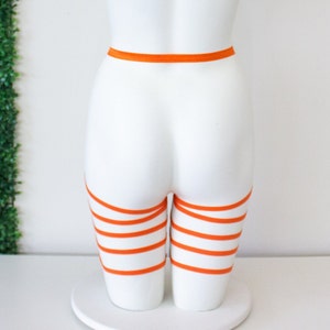 Op de afbeelding: Oranje dijbeenkousen met een bijpassende tailleband. De kousen zijn gemaakt van een zacht, rekbaar materiaal en zijn verstelbaar om te passen bij de meeste maten.
