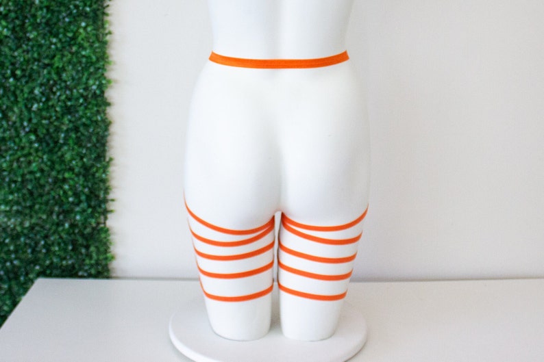 Op de afbeelding: Oranje dijbeenkousen met een bijpassende tailleband. De kousen zijn gemaakt van een zacht, rekbaar materiaal en zijn verstelbaar om te passen bij de meeste maten.