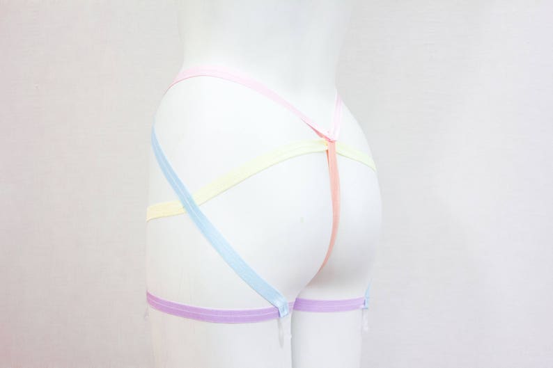 May include: A pastel-colored garter belt with a light blue, yellow, pink, and purple ribbon design.