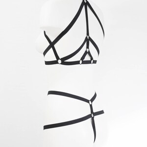 May include: Black lingerie set with straps and rings. The set includes a bra and a panty.