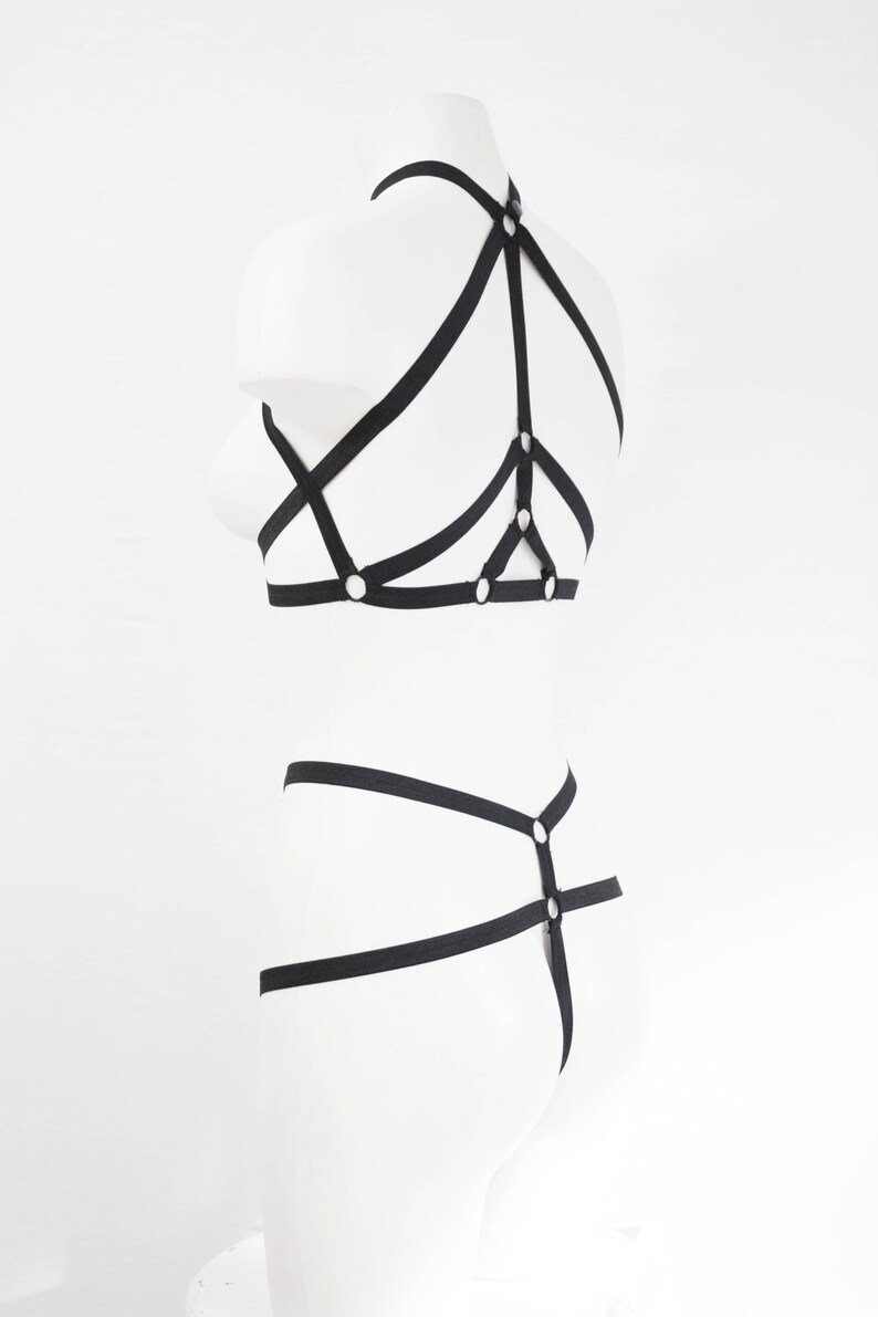May include: Black lingerie set with straps and rings. The set includes a bra and a panty.