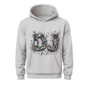 Puede incluir: Una sudadera con capucha gris claro con un bolsillo delantero y una capucha. La parte delantera de la sudadera presenta la palabra "DJ" en un diseño artístico y colorido. Las letras están llenas de notas musicales, equipos de sonido y otros elementos relacionados con la música.