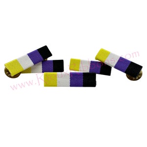 Pode incluir: Quatro alfinetes de fita amarela, branca, roxa e preta. Os alfinetes medem aproximadamente 5 cm de comprimento e têm um suporte de metal dourado.