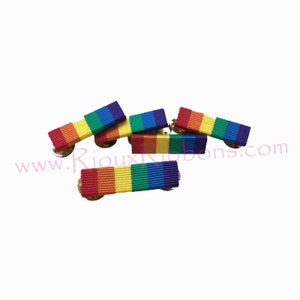May include: Five rainbow ribbon pins with gold metal clasps. The ribbons are red, orange, yellow, green, blue, and purple.