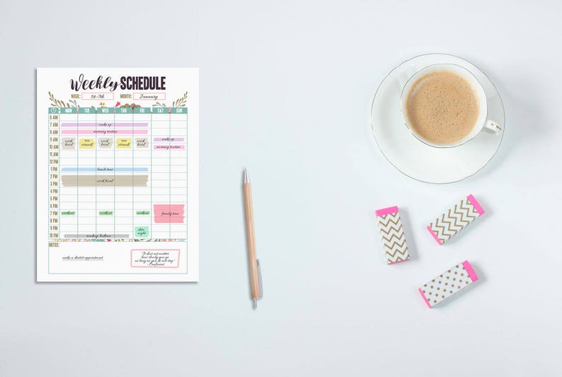 May include: A weekly schedule planner with a cup of coffee, a pen, and three erasers. The planner has a colorful layout with the words "Weekly Schedule" at the top. The erasers have a white base with gold chevron and pink accents.
