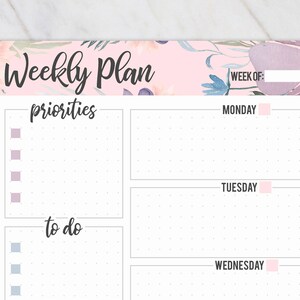 May include: A weekly planner with a floral design in pink, purple, and blue. The top of the planner reads "Weekly Plan" in black script. It includes sections for priorities and to-do lists, with spaces for each day of the week.