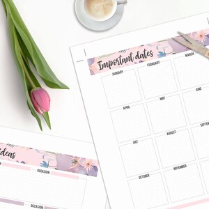 May include: A planner with floral accents, featuring sections for "Important Dates" and "Gift Ideas." A pink tulip and gold scissors are on the white surface. A cup of coffee and a keyboard are also visible.