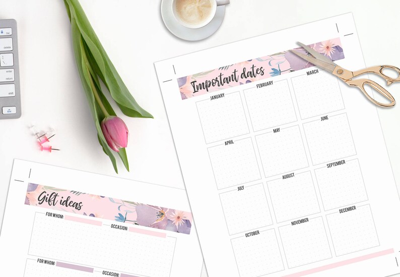 May include: A planner with floral accents, featuring sections for "Important Dates" and "Gift Ideas." A pink tulip and gold scissors are on the white surface. A cup of coffee and a keyboard are also visible.
