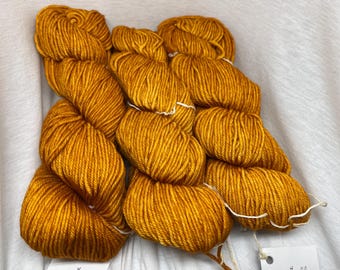 Könnte beinhalten: Eine Garnrolle in goldgelber Farbe, perfekt für Strick- oder Häkelprojekte.