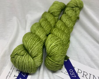 Könnte beinhalten: Zwei Knäuel grünes Garn, beschriftet mit "PRINT 037" und einer Nadelstärkenempfehlung von US 4-6. Das Garn ist 164 Yards (150 Meter) lang und besteht aus 80% Superwash.