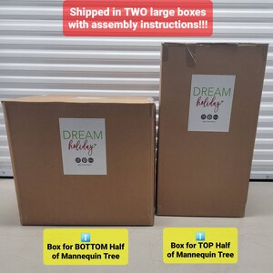 Op de afbeelding: Twee bruine kartonnen dozen met de tekst "DREAM holiday" erop gedrukt. De dozen zijn gelabeld "Doos voor de onderste helft van de Mannequin Boom" en "Doos voor de bovenste helft van de Mannequin Boom".