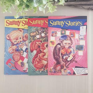 Three vintage children's activity books with colorful covers. The covers feature a bear, a squirrel, and a monkey, each holding a paintbrush and palette. The books are titled "Sunny Stories" and have a price of 6 pence.
