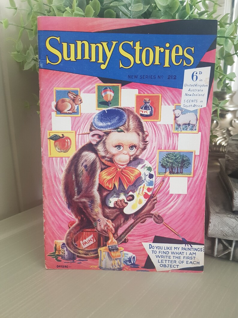 A vintage children's activity book cover featuring a cartoon monkey painting with a paintbrush and a palette. The cover is pink with a blue title "Sunny Stories" and a price of 6d. The text below the monkey says "Do you like my paintings? To find what I am write the first letter of each object."