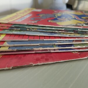 A stack of vintage comic books with colorful covers. The top cover features a cartoon illustration of a man and a woman in a playful scene.