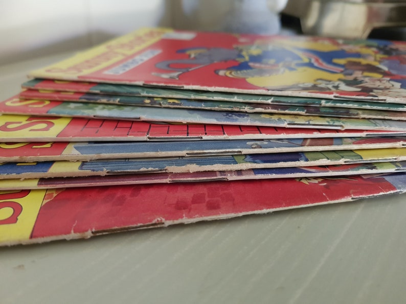 A stack of vintage comic books with colorful covers. The top cover features a cartoon illustration of a man and a woman in a playful scene.
