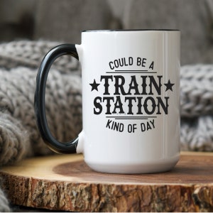 May include: White ceramic mug with a black handle and black text that reads "Could be a Train Station Kind of Day".