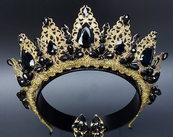 May include: A gold crown with black gemstones and matching earrings. The crown is made of delicate wirework and features a pointed design.